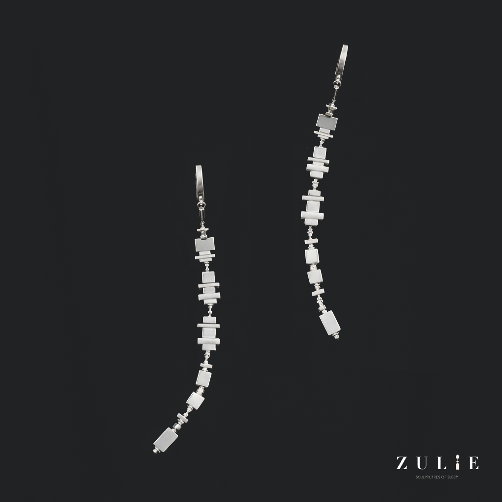 A pair of long silver ZULIE earrings shaped from sleep data